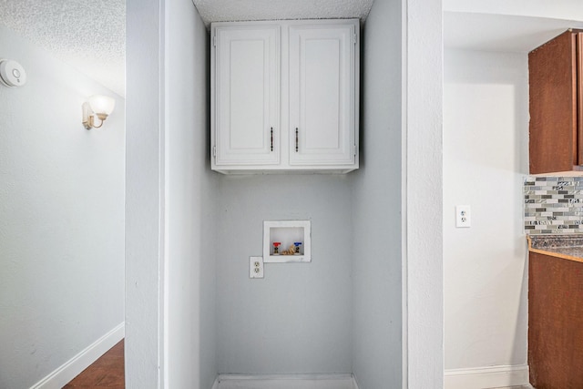 washroom featuring cabinet space, baseboards, and washer hookup