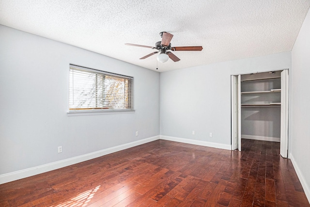 unfurnished bedroom featuring wood-type flooring, baseboards, a walk in closet, and a textured ceiling