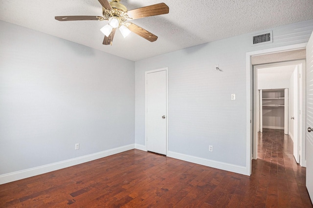 unfurnished bedroom with baseboards, a textured ceiling, visible vents, and wood finished floors