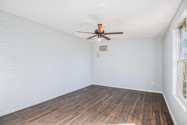 spare room with dark wood-type flooring, baseboards, brick wall, and a ceiling fan