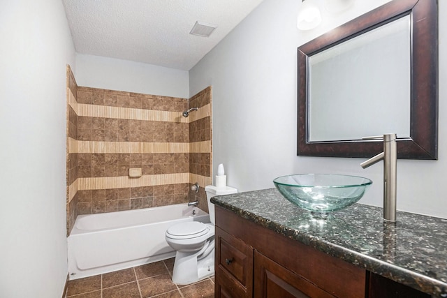 bathroom with visible vents, toilet, vanity, a textured ceiling, and tile patterned flooring