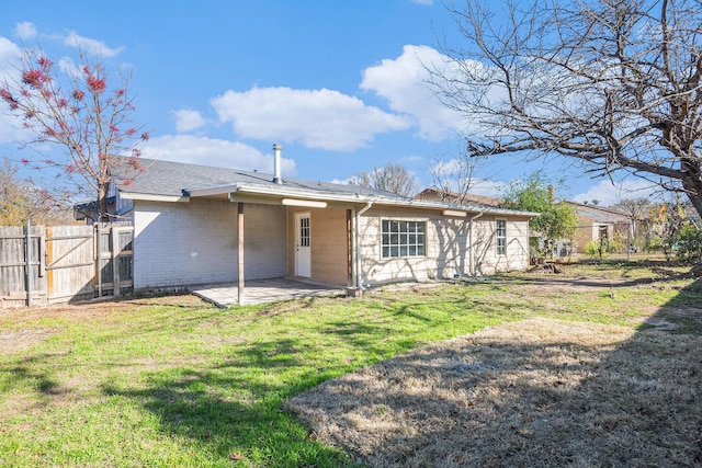 back of property with brick siding, fence, a lawn, and a patio