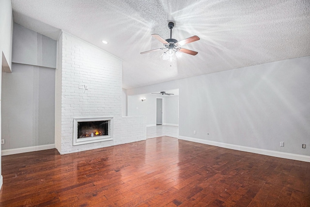 unfurnished living room featuring lofted ceiling, a textured ceiling, and a brick fireplace