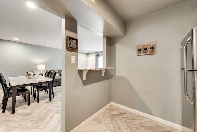 kitchen with light parquet flooring, stainless steel fridge, and kitchen peninsula