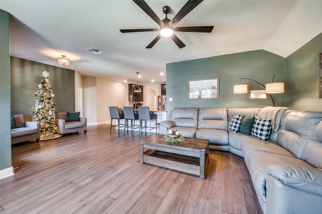 living room with hardwood / wood-style flooring, ceiling fan, and vaulted ceiling