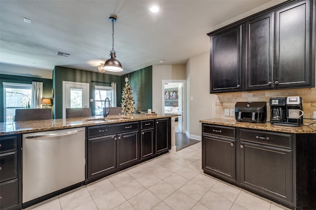 kitchen with stone counters, dishwasher, sink, hanging light fixtures, and backsplash