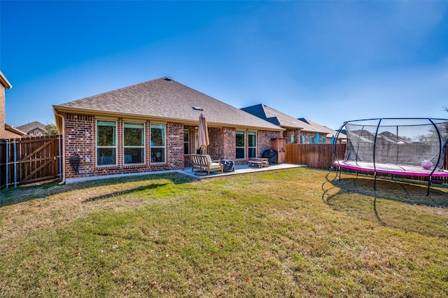 back of property with an outdoor fire pit, a patio area, a yard, and a trampoline