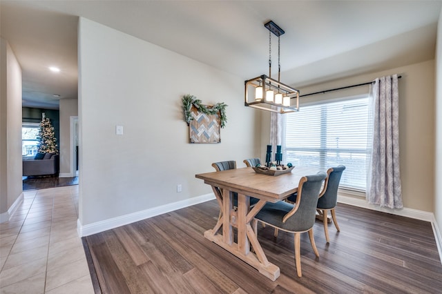 dining area featuring wood-type flooring, a wealth of natural light, and a notable chandelier