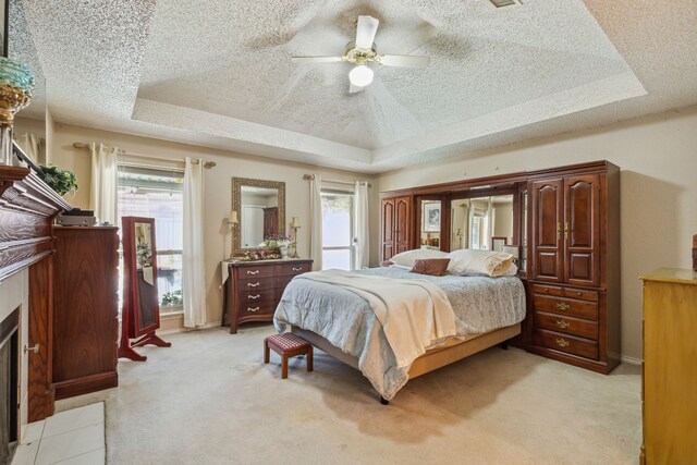 bedroom with a raised ceiling, multiple windows, and ceiling fan