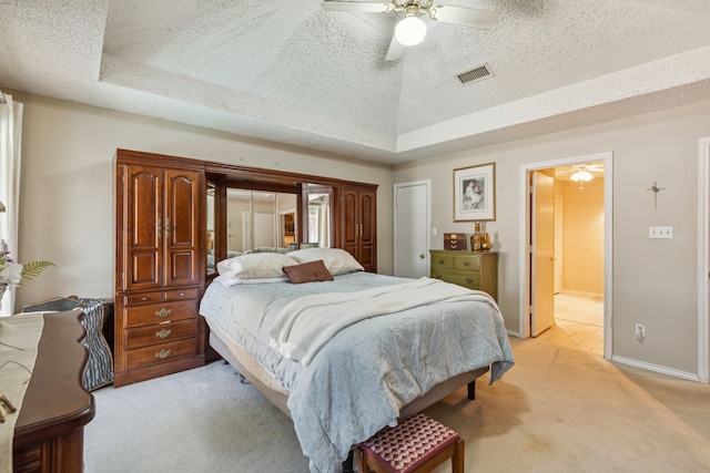 carpeted bedroom with ceiling fan, a textured ceiling, and a tray ceiling