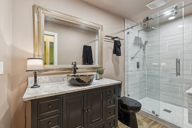 bathroom featuring hardwood / wood-style flooring, vanity, toilet, and a shower with door