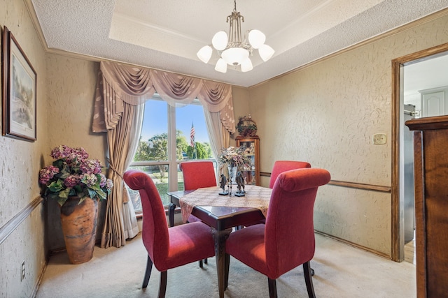 carpeted dining room featuring a chandelier, a textured ceiling, a tray ceiling, and ornamental molding