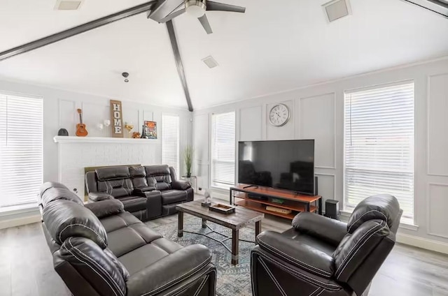 living room with ceiling fan, light hardwood / wood-style floors, and vaulted ceiling with beams