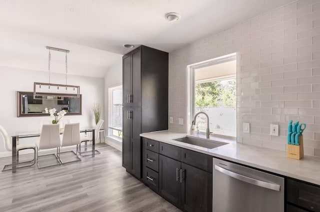 kitchen with stainless steel dishwasher, pendant lighting, sink, and light hardwood / wood-style flooring