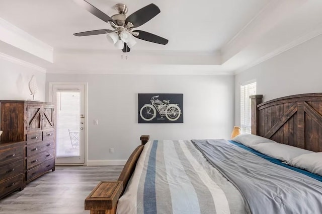 bedroom with hardwood / wood-style flooring, a raised ceiling, ceiling fan, and crown molding