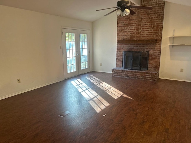 unfurnished living room featuring lofted ceiling, dark wood-type flooring, french doors, a brick fireplace, and ceiling fan