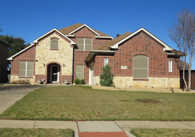 view of front of home with brick siding, a front lawn, an attached garage, and stone siding