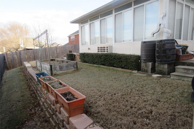 view of side of home featuring fence, a yard, and a garden