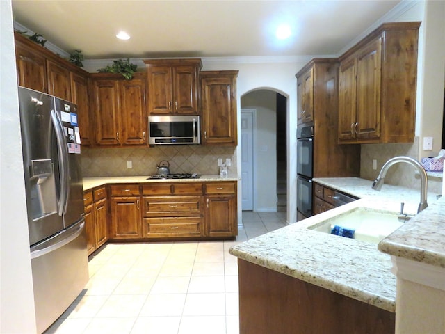 kitchen with a sink, stainless steel appliances, arched walkways, light tile patterned flooring, and ornamental molding