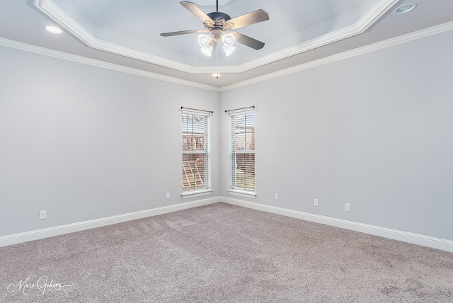 carpeted empty room with a raised ceiling, ceiling fan, and crown molding