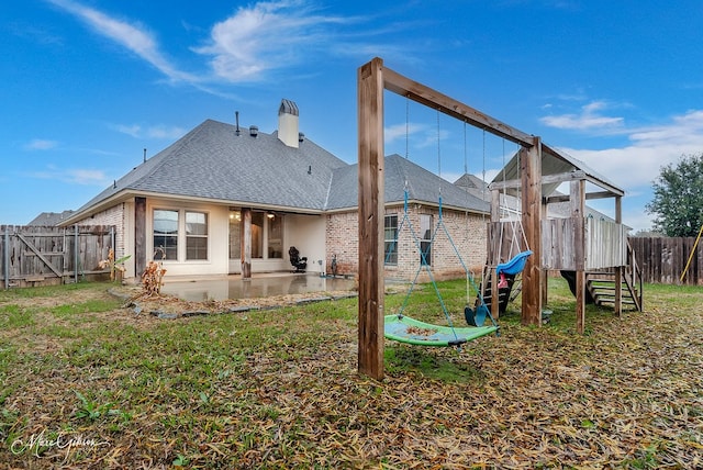 back of house featuring a lawn, a playground, and a patio