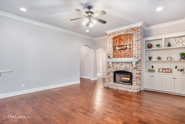 unfurnished living room with hardwood / wood-style flooring, a brick fireplace, ceiling fan, and crown molding