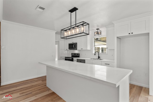 kitchen with hanging light fixtures, a kitchen island, light hardwood / wood-style floors, white cabinetry, and stainless steel appliances