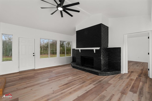 living room featuring a brick fireplace, ceiling fan, lofted ceiling with beams, and light wood-type flooring