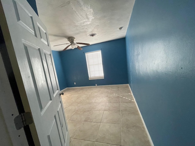 tiled empty room with a textured ceiling and ceiling fan