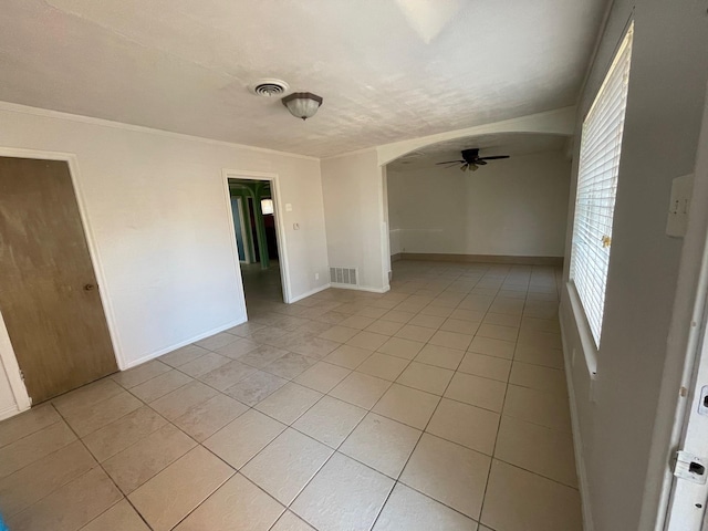 empty room featuring light tile patterned flooring, ornamental molding, and ceiling fan