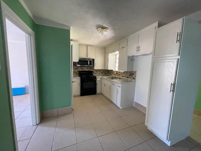 kitchen with sink, black range oven, light tile patterned flooring, backsplash, and white cabinets