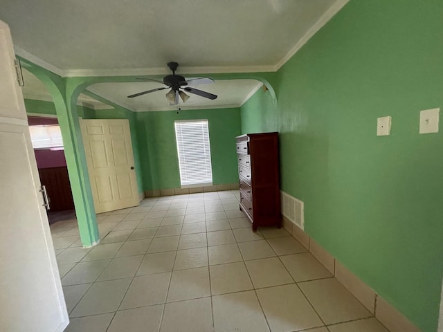 empty room with ceiling fan, ornamental molding, and light tile patterned floors