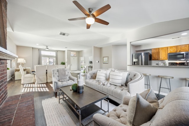 living room featuring a fireplace, wood-type flooring, and ceiling fan