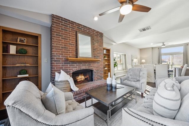 living room with a brick fireplace, ceiling fan, hardwood / wood-style flooring, and vaulted ceiling