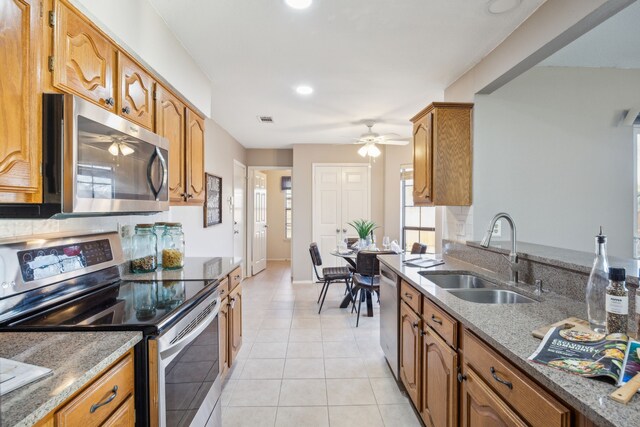 kitchen with dark stone countertops, sink, light tile patterned floors, and stainless steel appliances