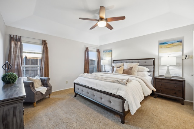 carpeted bedroom with a raised ceiling and ceiling fan