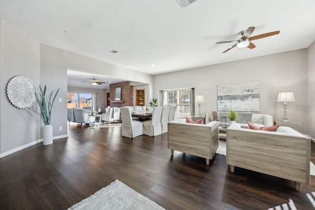 living room with a wealth of natural light, ceiling fan, and dark wood-type flooring