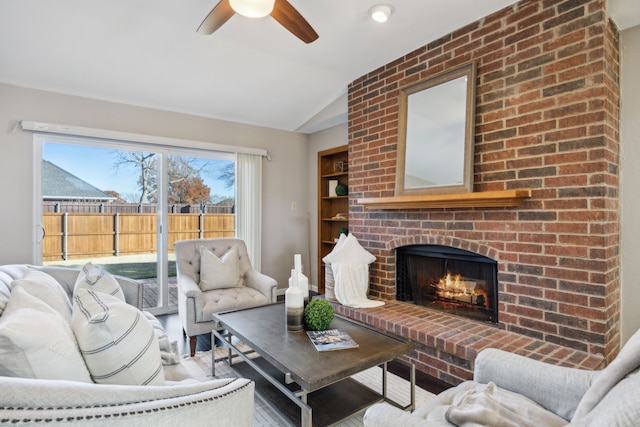 living room featuring ceiling fan, a fireplace, and vaulted ceiling