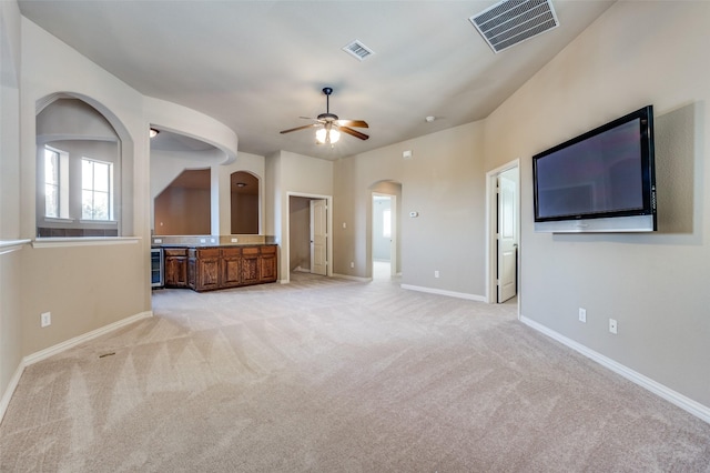 unfurnished living room with light colored carpet, ceiling fan, and beverage cooler