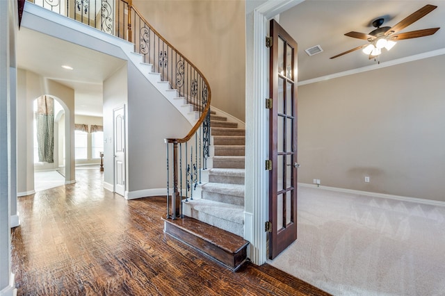 stairs featuring a high ceiling, ornamental molding, hardwood / wood-style floors, and ceiling fan