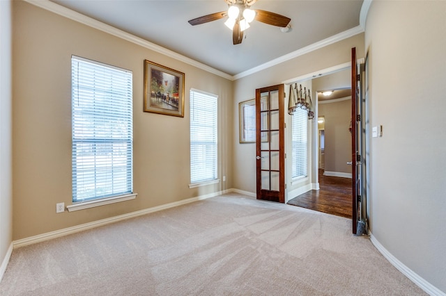 empty room featuring ceiling fan, crown molding, light carpet, and french doors