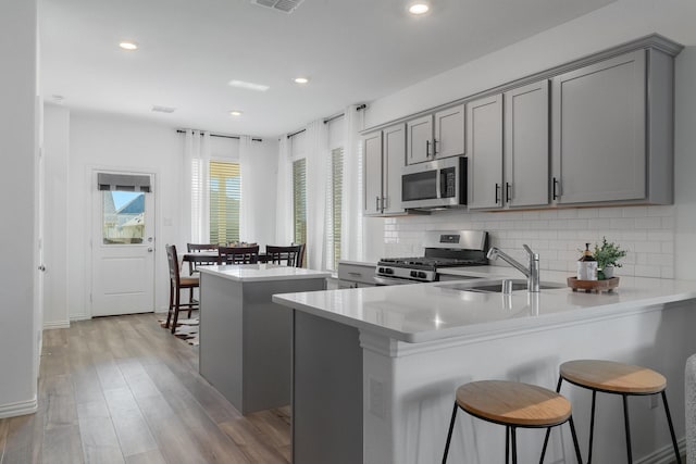 kitchen featuring kitchen peninsula, appliances with stainless steel finishes, gray cabinetry, and sink