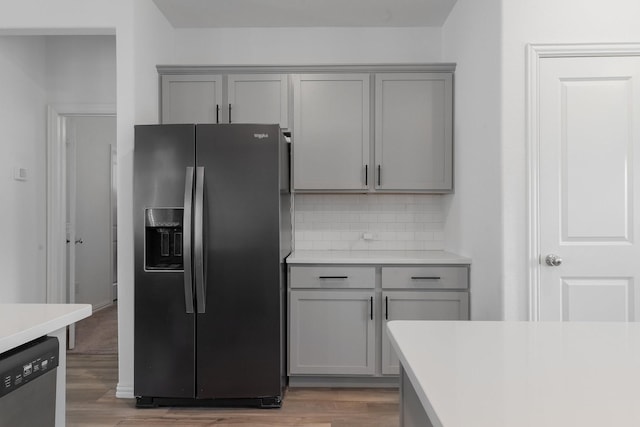 kitchen with appliances with stainless steel finishes, tasteful backsplash, gray cabinets, and light hardwood / wood-style flooring