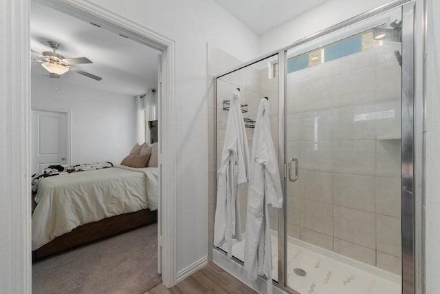 bathroom featuring a healthy amount of sunlight, ceiling fan, a shower with shower door, and wood-type flooring