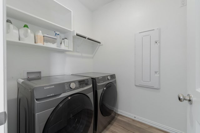 washroom featuring hardwood / wood-style flooring, washer and dryer, and electric panel