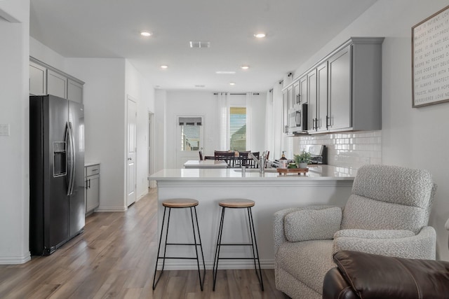 kitchen with kitchen peninsula, appliances with stainless steel finishes, backsplash, and gray cabinetry