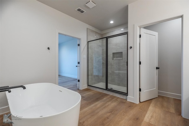 bathroom featuring hardwood / wood-style flooring and plus walk in shower