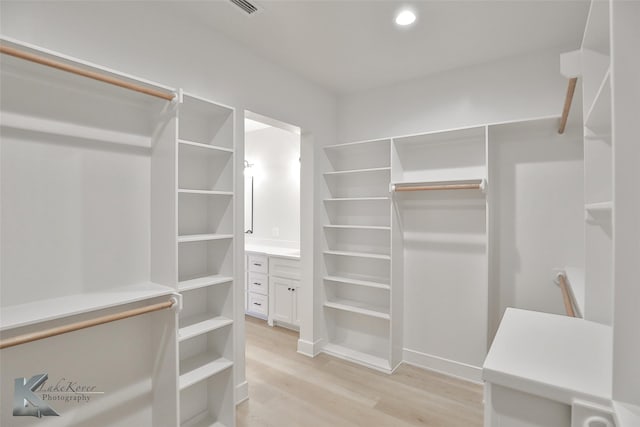 walk in closet with light hardwood / wood-style floors