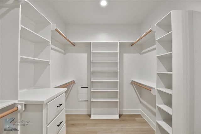 walk in closet with light hardwood / wood-style floors