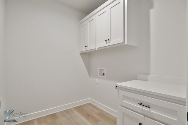 washroom with hookup for a washing machine, light hardwood / wood-style flooring, and cabinets